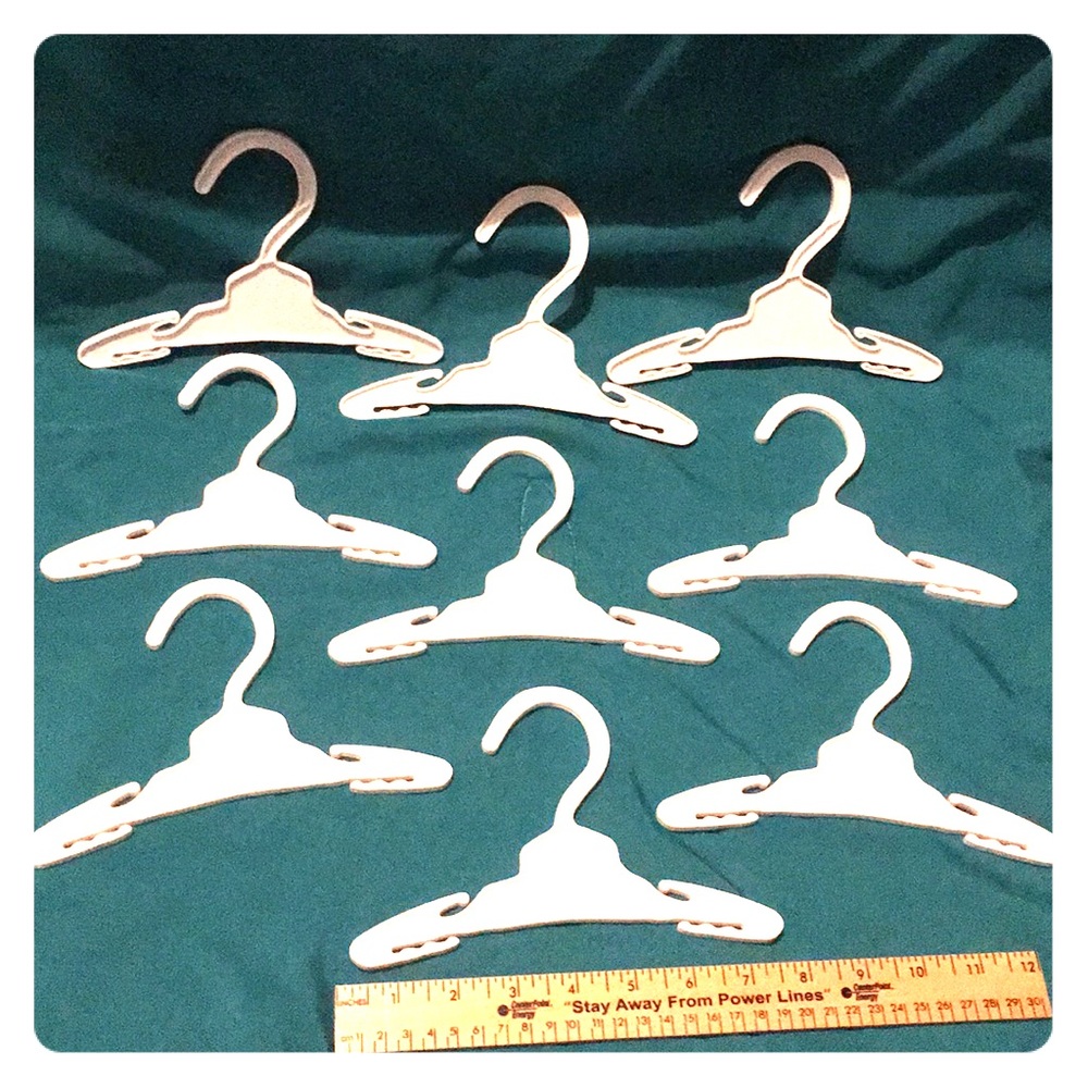 Nine white hangers for doll clothes